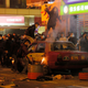 Rioters throw bricks at police in Mong Kok during the Lunar New Year riots. The car is an abandoned taxi cab.